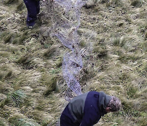 Two expeditioners trying to roll up old netting