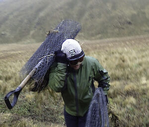 Expeditioner carrying large roll of old wire netting