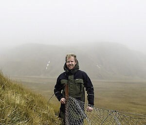 Ranger stands beside wire netting exclosure