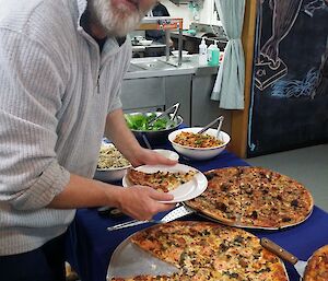 An expeditioner helps himself to a slice of the “posh pizza”