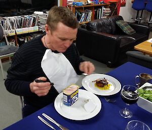 Chris has a choice of entrees as he sits at a table and pretends to open a can of Spam with a knife and fork