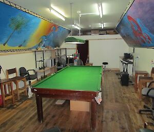 Inside recreation hut with colourful artworks on the wall and a pool table in the centre of the room