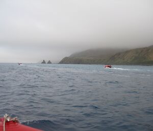Heading south in the IRBs, several expeditioners and boats are seen in water with green hills behind