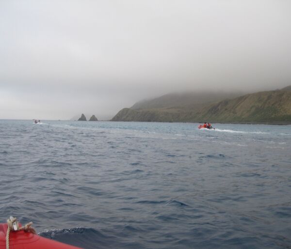 Heading south in the IRBs, several expeditioners and boats are seen in water with green hills behind
