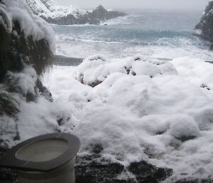 Folding toilet seat on bucket, surrounded by sea foam