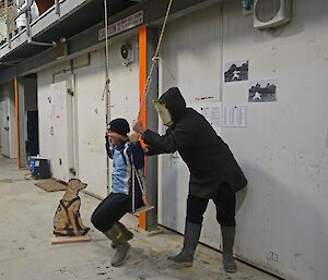 One epeditioner pushes another on a swing in the warehouse