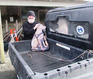 Expeditioner holds up cardboard cutout of plastic labrador dog in back of polaris vehicle