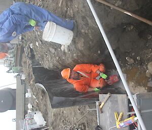 Pat and Ben applying bentonite to the floor of the trench