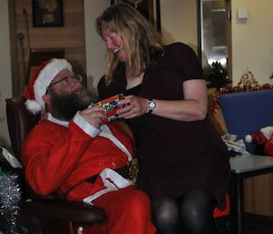 Female expeditioner sitting on Santa’s knee receiving her present