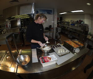 A female expeditioner assisting withteh preparation of food for Christmas dinner