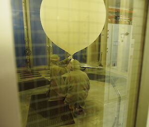 An expeditioner filling the Met Balloon with hydrogen with the Director watching