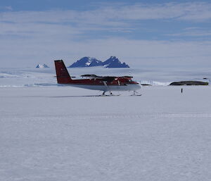 Twin Otter KBC preparing to take off on the sea-ice with the Antarctic plateau and David Range behind