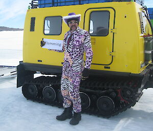 An expeditioner wearing a lurid suit accompanied by tie and hat preapring to greet the Director