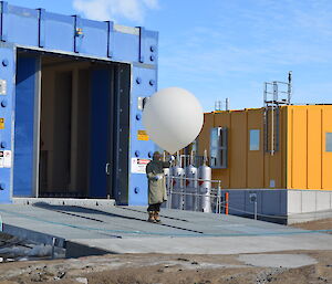 Director standing on the concrete apron outside the Balloon Shed preparing to release the balloon with the sonde attached