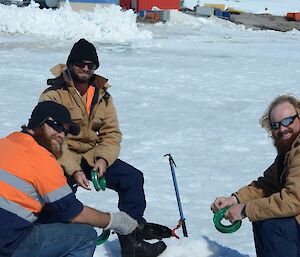 Three expeditioners sitting on flour drums with hand lines