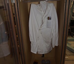 A white laboratory coat and on the floor a pistol, bar of chocolate, a pait of safety glasses and a slide ruler