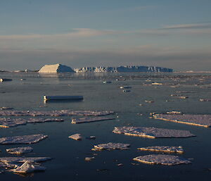 A view of brash ice, small ice floes and a large iceberg in the distance