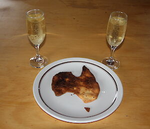 A biscuit in the shape of Australia with 2 glasses of champagne
