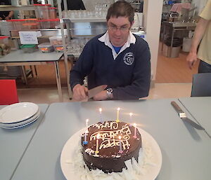 An expeditioner with his chocolate birthday cake in front of him