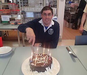 An expeditioner about to insert the knife into the cake before blowing out the candles