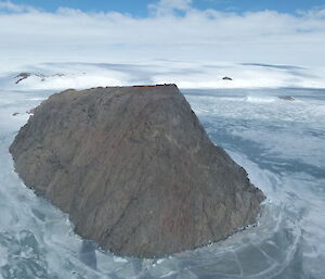 A jagged rocky island surrounded by sea-ice with ice plateau behind