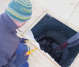 Expeditioner measuring the depth of water in the melt bell cavern