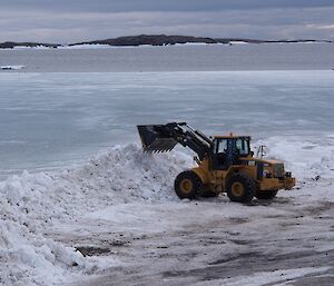 Expeditioner in loader moving snow