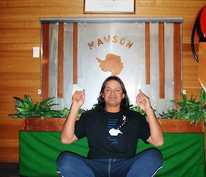 Cliff at Mawson sitting inside, underneath a photo of Sir Douglas Mawson and the station’s wood and metal Mawson sign