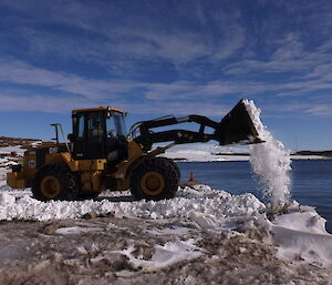 A large excavator is clearing snow