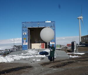 An expeditioner holds a large white balloon before release