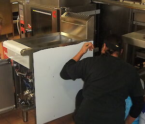 Two expeditioners installing large industrial kitchen equipment