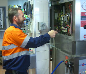 Peter C in work uniform pointing a screwdriver at a part of the new oven that has lights and wires