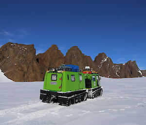 David Range in background with bright green Hägglunds in snow in foreground