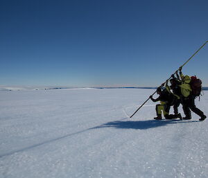 Replacing navigational cane, four expeditioners on ice lifting a pole into place