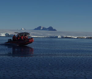 A long shot of boating on pancake ice on a bright sunny day with ice plateau in background
