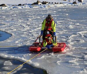 Rescue Alive recovery exercise — a small floating device with two expeditioners aboard is pulled by rope from sea ice and water