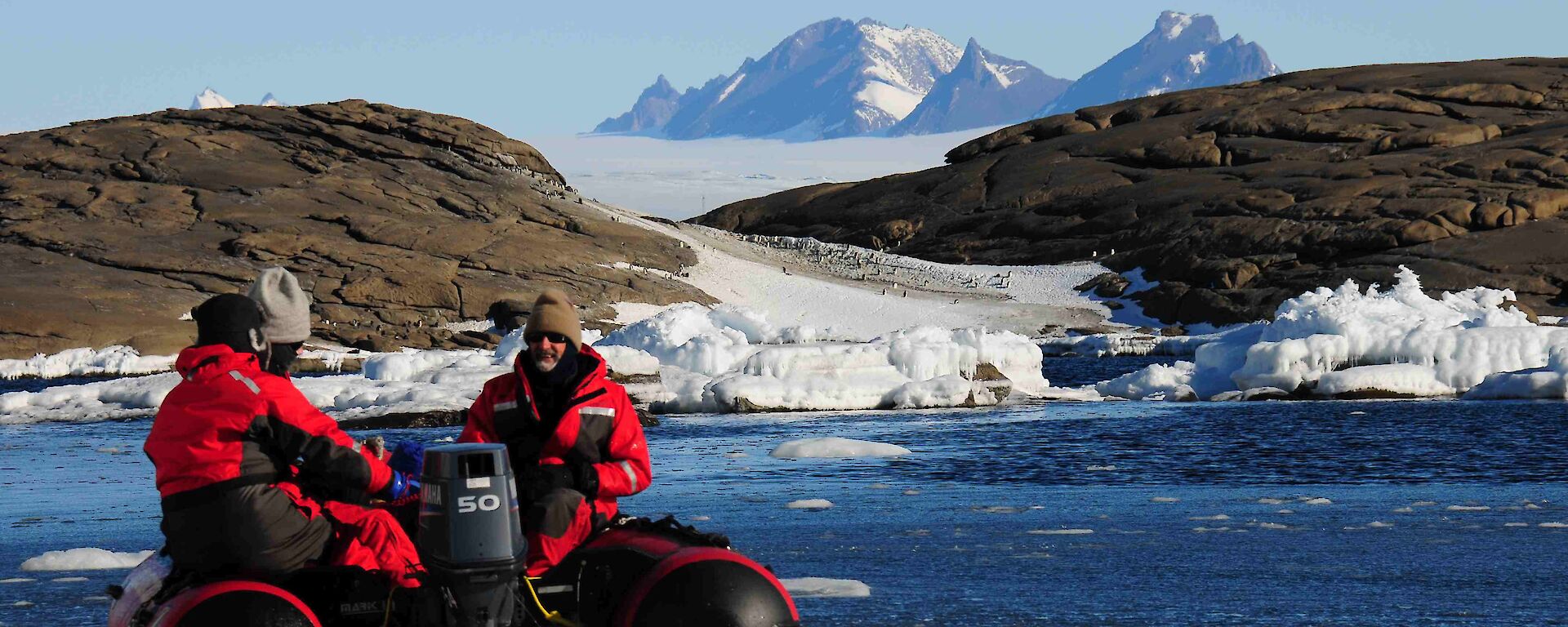 Expeditioners in a small inflatable rubber boat with land and ice in background