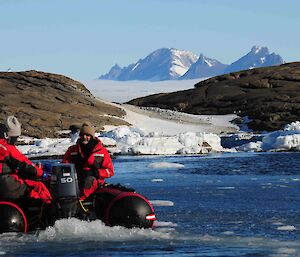 Expeditioners in a small inflatable rubber boat with land and ice in background