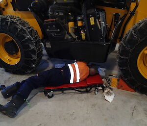 Geoff working on loader, on his back underneath it in workshop