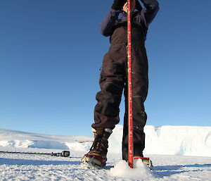 Checking ice thickness using a pole to measure