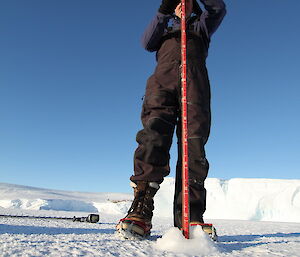 Checking ice thickness using a pole to measure