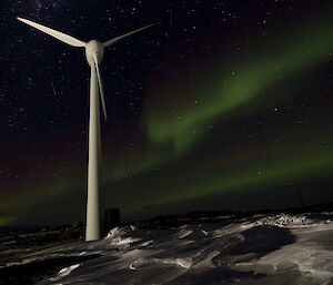 Aurora at Mawson — wind turbine in foreground with big green aurora in background