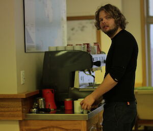Keldyn Francis turns to look at the camera while making a coffee