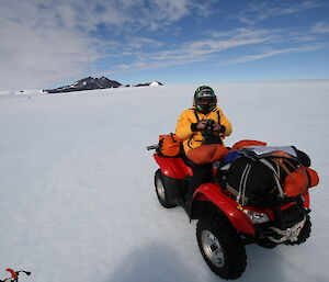 Expeditioner on the ice on a quad bike with a camera