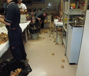 Onions dropped on floor are sorted by an expeditioner while two others sort onions on a table