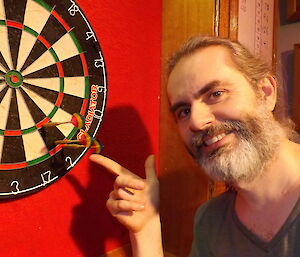 Darron pointing at a line of darts in the board