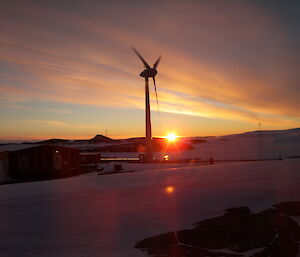 Sunset at Mawson featuring the large wind turbine, backlit by a multi-coloured sky