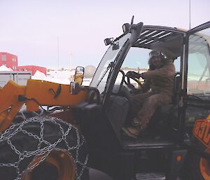 A male expeditioner drives a JCB, a large tractor with chains on the tyres