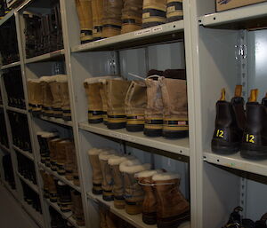 Boots in shelves line a large section of a wall in the field storage building