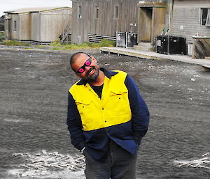 Cliff Simpson-Davis on Macquarie Island, posing outdoors on station with pink goggles